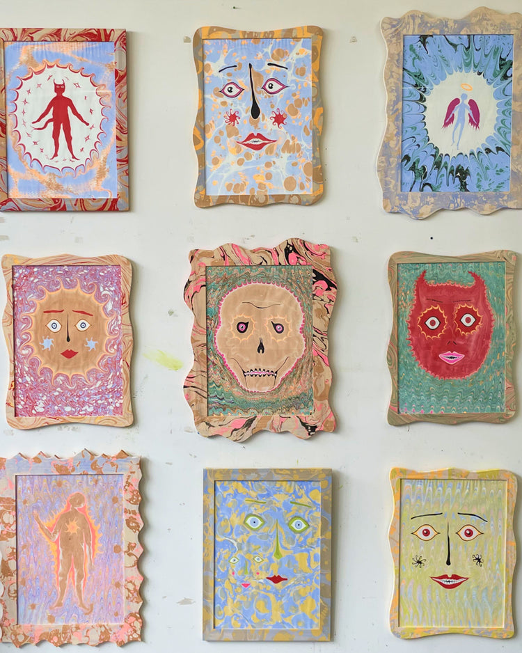 Nine small colorful abstract art pieces with stylized faces and figures arranged in a grid on a white wall.